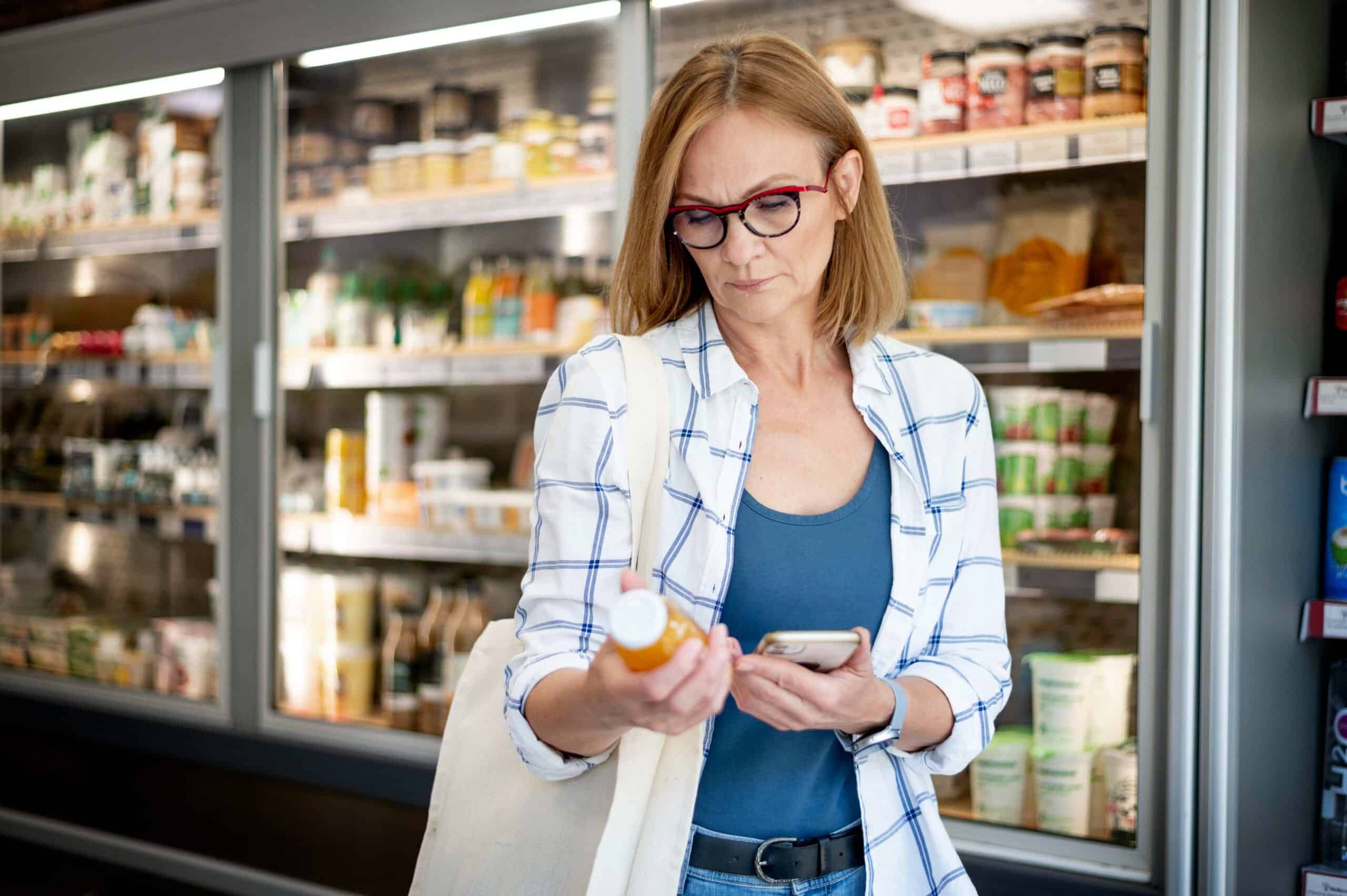 Woman checking product details in grocery store, focus on eco-friendly shopping.